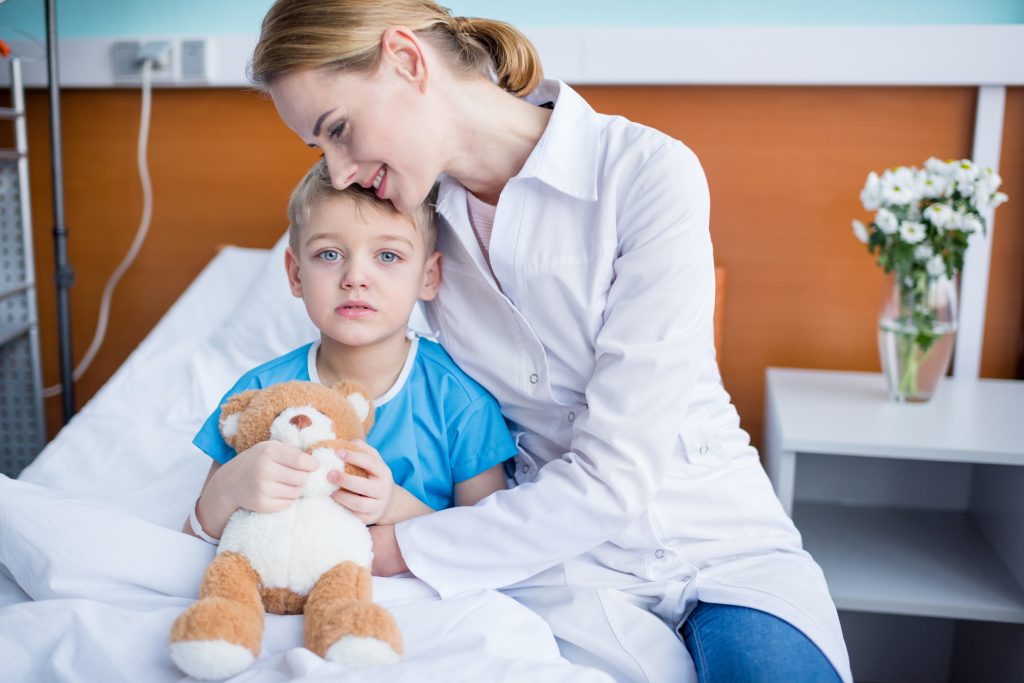 Mutter und Kind warten im Krankenhaus auf den Arzt währenddessen beruhigt die Mutter das Kind